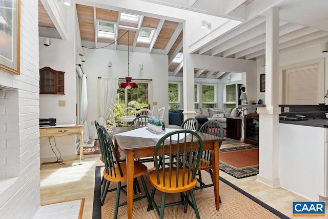 dining room with a healthy amount of sunlight, wood ceiling, high vaulted ceiling, and light hardwood / wood-style flooring