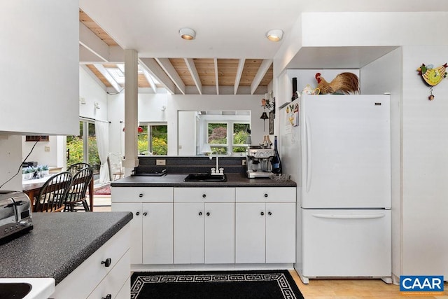 kitchen featuring a healthy amount of sunlight, sink, white cabinets, and white fridge