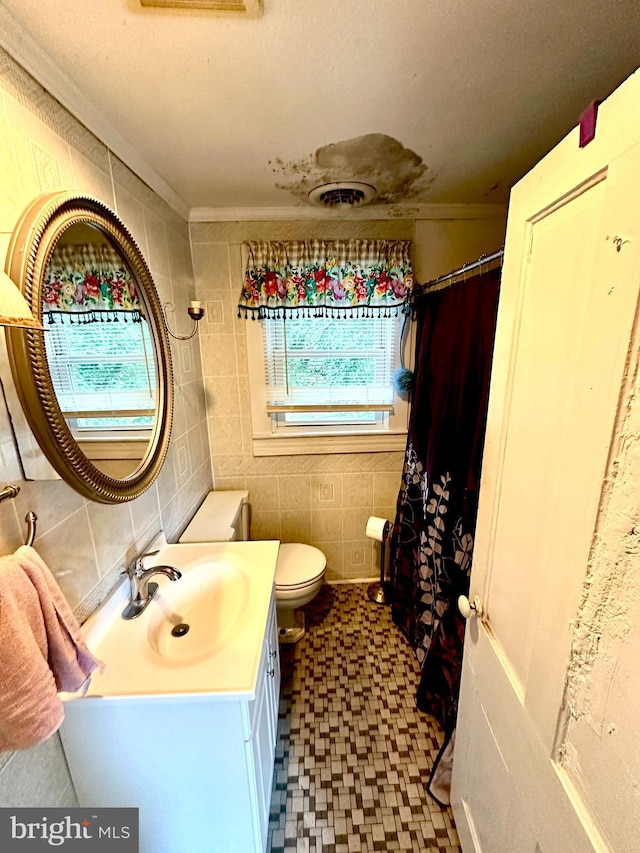 bathroom featuring ornamental molding, vanity, toilet, and tile walls