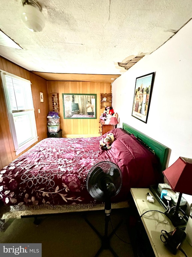 bedroom with a textured ceiling and wooden walls