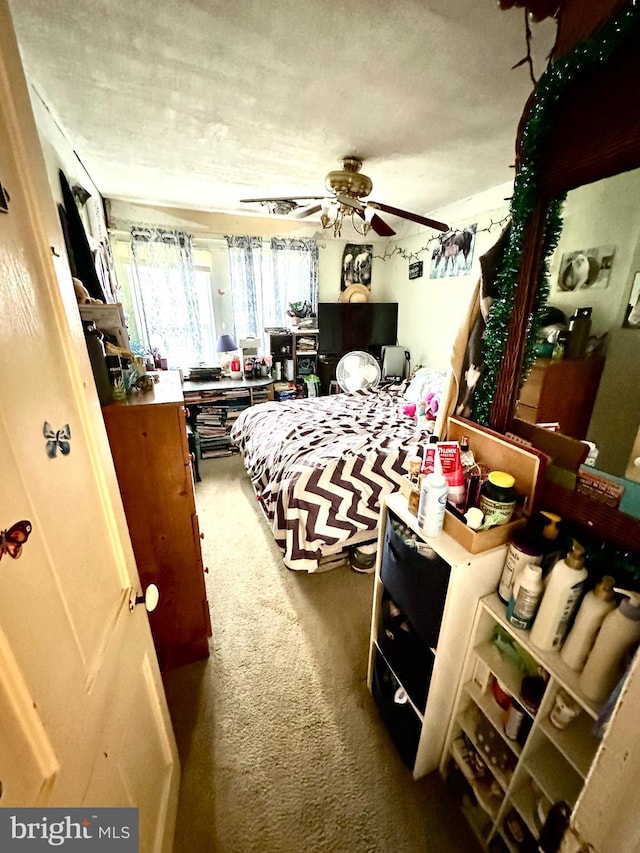 carpeted bedroom featuring ceiling fan and a textured ceiling