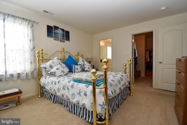 bedroom with a walk in closet, multiple windows, light carpet, and a closet