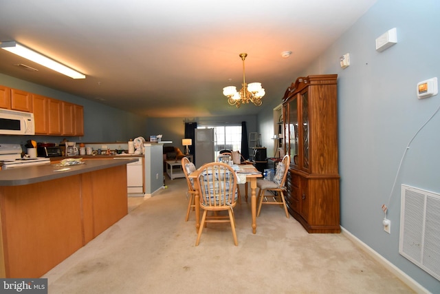 kitchen featuring white appliances, light colored carpet, a chandelier, and decorative light fixtures