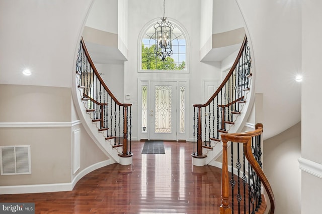 foyer with hardwood / wood-style flooring, a chandelier, and a high ceiling