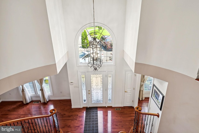 entrance foyer featuring a towering ceiling, dark hardwood / wood-style floors, and a chandelier