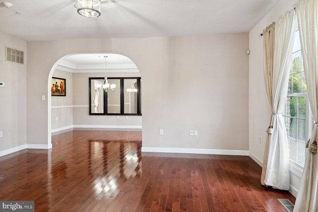 spare room featuring a notable chandelier and dark wood-type flooring