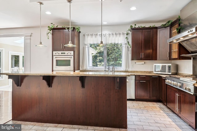 kitchen with light stone countertops, stainless steel appliances, a center island, and a kitchen bar