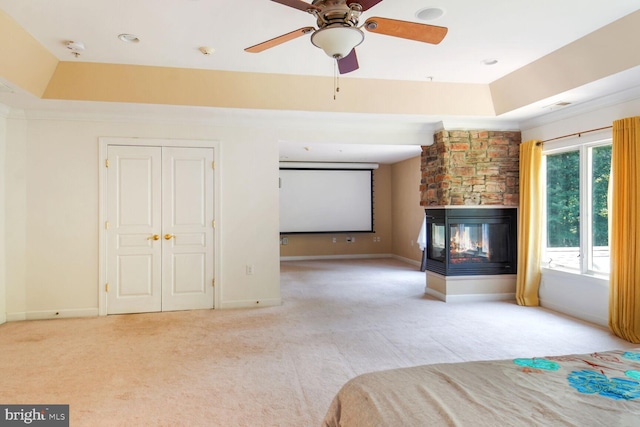 unfurnished bedroom featuring light carpet, ornamental molding, a raised ceiling, a closet, and a fireplace