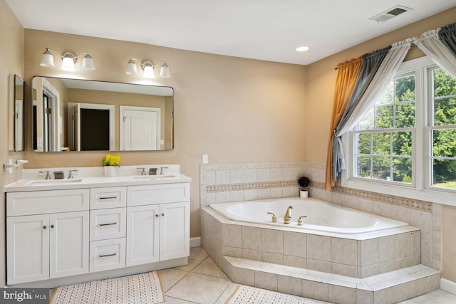 bathroom featuring tile patterned flooring, vanity, and tiled bath