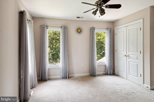 spare room with ceiling fan and light carpet