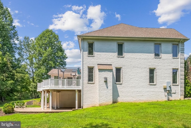 rear view of house featuring a wooden deck, a yard, and a patio