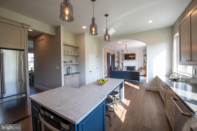 kitchen featuring built in shelves, dark wood-type flooring, a breakfast bar, a center island, and stainless steel appliances