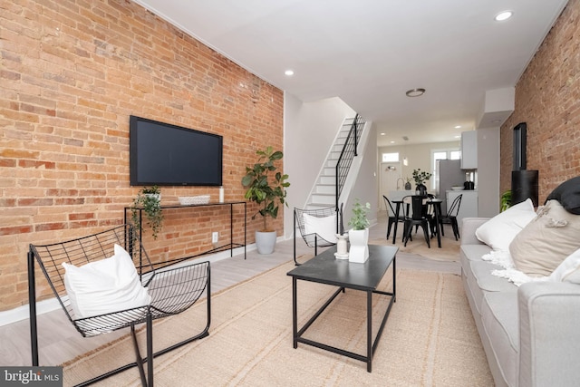 living room featuring light wood-type flooring, a wood stove, and brick wall