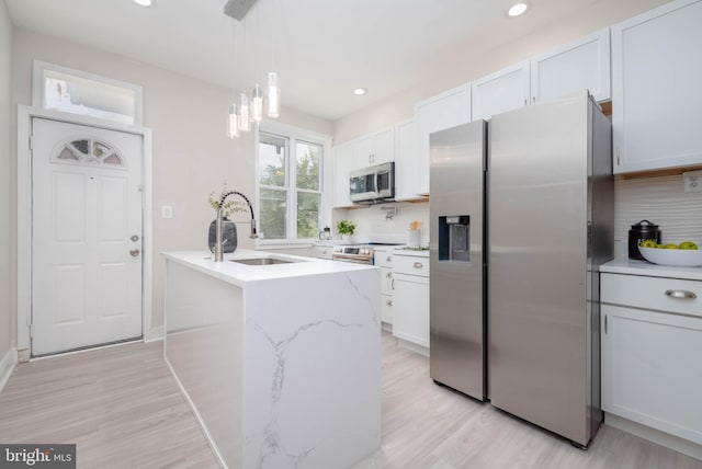 kitchen featuring pendant lighting, white cabinetry, sink, a kitchen island with sink, and stainless steel appliances