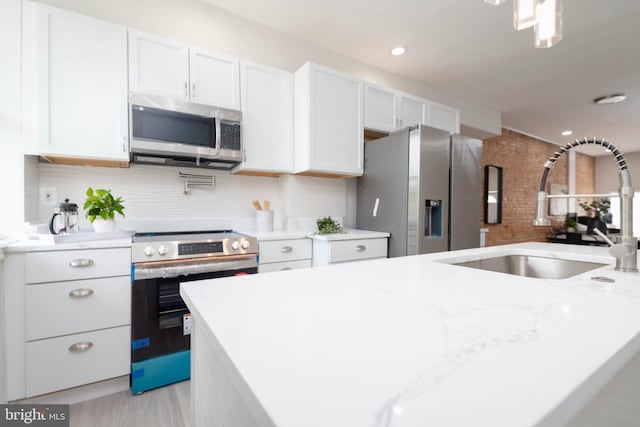 kitchen featuring sink, appliances with stainless steel finishes, backsplash, light stone counters, and white cabinets