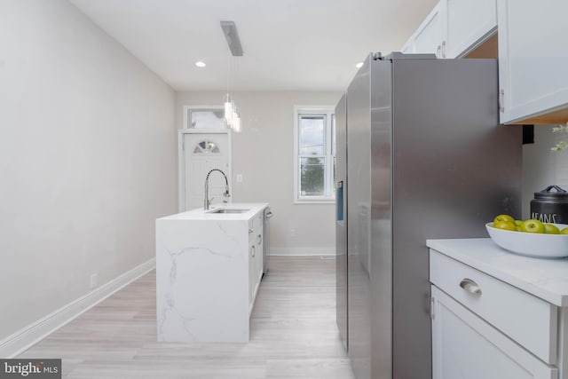 kitchen featuring sink, stainless steel refrigerator with ice dispenser, light stone countertops, white cabinets, and decorative light fixtures