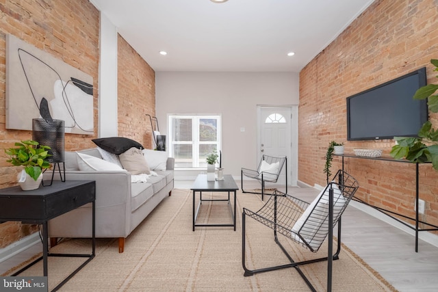 living room with light hardwood / wood-style flooring and brick wall