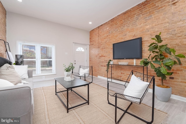 living room featuring brick wall and light hardwood / wood-style floors