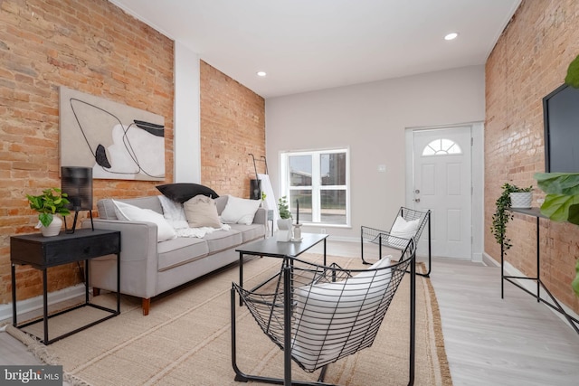 living room featuring brick wall and light hardwood / wood-style floors