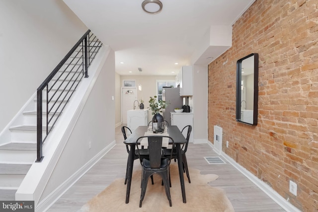 dining area featuring light hardwood / wood-style flooring and brick wall