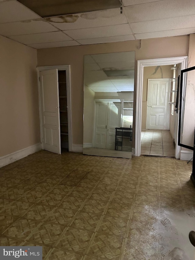 interior space with a paneled ceiling and tile patterned floors