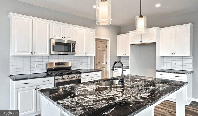 kitchen featuring light hardwood / wood-style floors, tasteful backsplash, sink, a center island with sink, and stainless steel electric stove