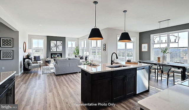 kitchen with dishwasher, sink, an island with sink, hardwood / wood-style flooring, and hanging light fixtures