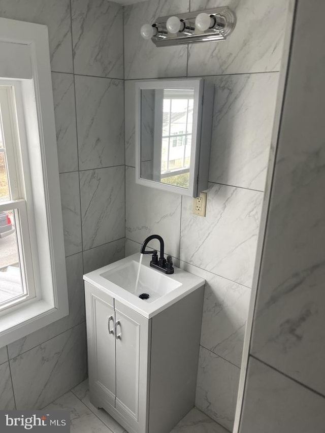 bathroom with vanity, a wealth of natural light, and tile walls