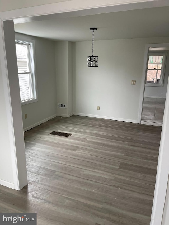 spare room with a notable chandelier and hardwood / wood-style floors