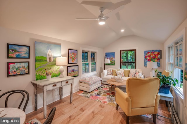 living room featuring ceiling fan, light wood-type flooring, and vaulted ceiling