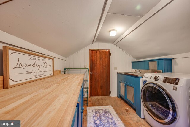 laundry area with sink, washer / dryer, light hardwood / wood-style flooring, and cabinets