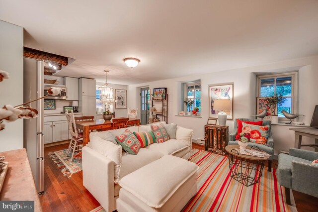 living room featuring baseboard heating, wood-type flooring, and an inviting chandelier