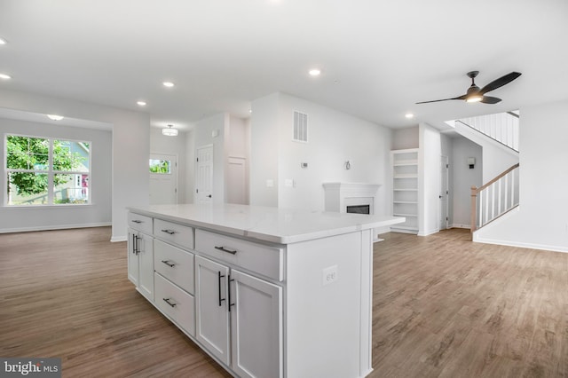 kitchen with white cabinetry, ceiling fan, light hardwood / wood-style floors, and a kitchen island