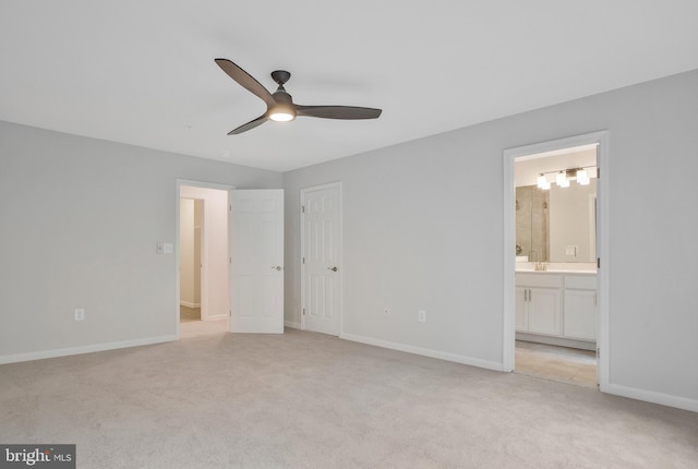 unfurnished bedroom featuring ceiling fan, sink, light colored carpet, and ensuite bath