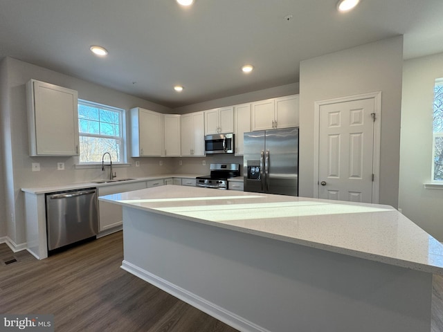 kitchen with white cabinetry, sink, stainless steel appliances, and a kitchen island