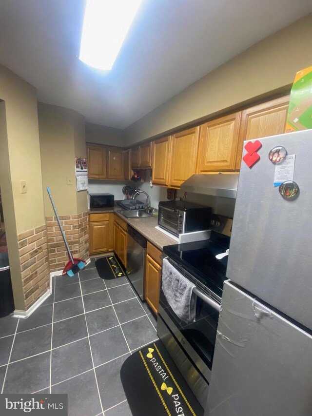 kitchen with lofted ceiling, ventilation hood, sink, dark tile patterned floors, and stainless steel appliances