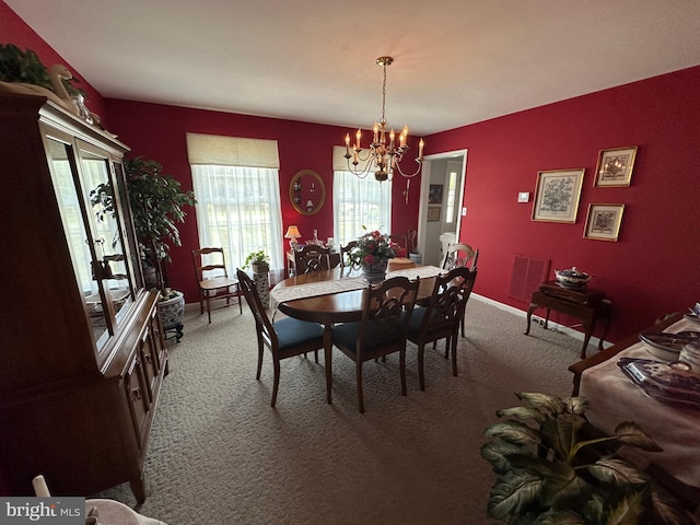 dining space with carpet floors and a chandelier