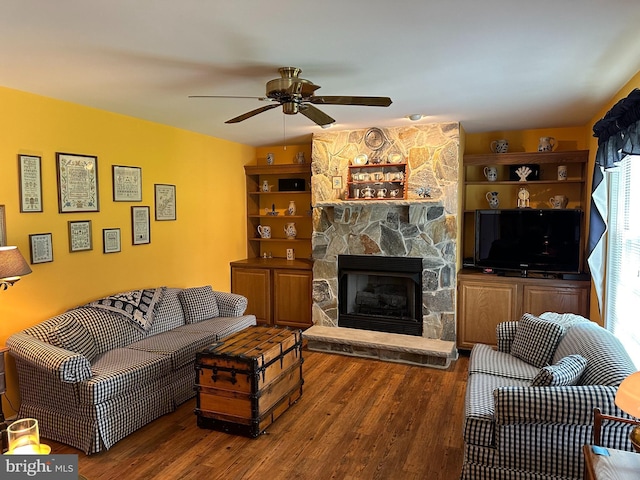 living room featuring ceiling fan, a fireplace, and dark hardwood / wood-style flooring