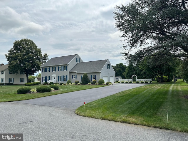 colonial-style house featuring a garage and a front lawn