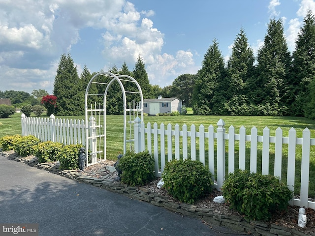 view of gate with a yard and a storage unit