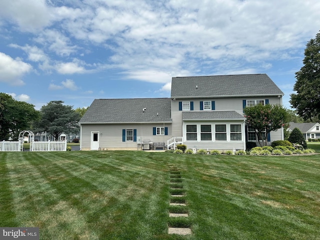 back of property with a lawn and a sunroom