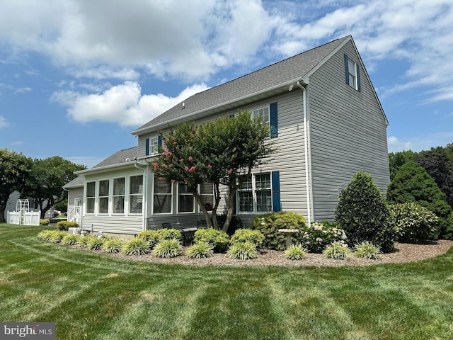 back of property with a sunroom and a yard