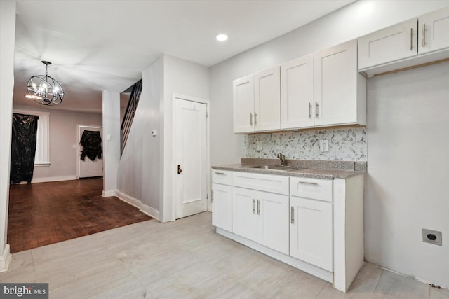 kitchen featuring sink, light hardwood / wood-style flooring, white cabinetry, and decorative backsplash