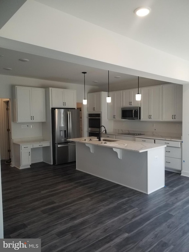 kitchen with appliances with stainless steel finishes, white cabinetry, hanging light fixtures, dark wood-type flooring, and a center island with sink