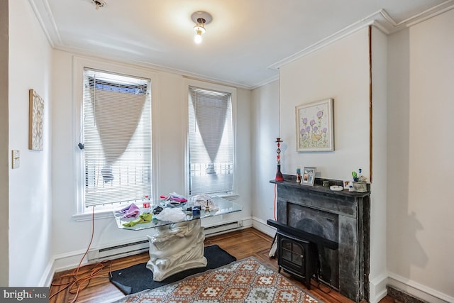 living area featuring crown molding, baseboard heating, and hardwood / wood-style flooring