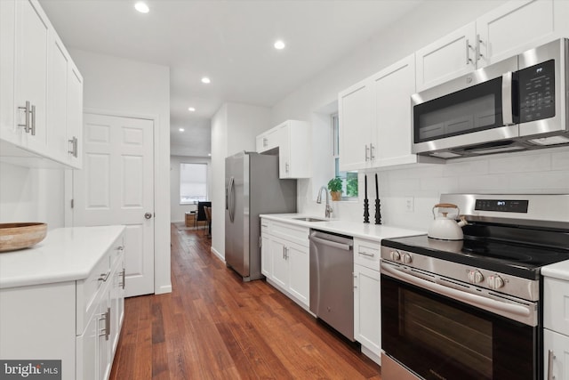 kitchen with white cabinets, dark wood-type flooring, appliances with stainless steel finishes, decorative backsplash, and sink