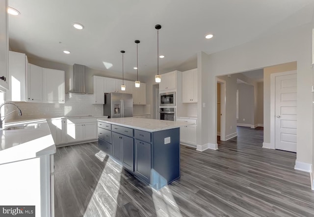 kitchen with wall chimney range hood, sink, stainless steel appliances, a center island, and white cabinets