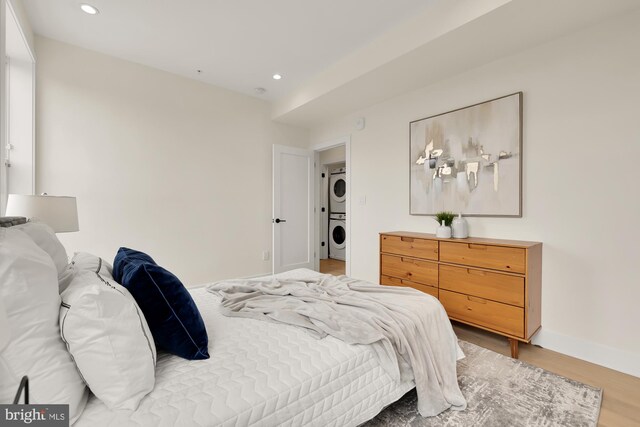 bedroom featuring stacked washer and clothes dryer and wood-type flooring