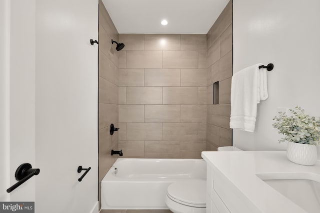 full bathroom featuring tiled shower / bath combo, toilet, and vanity