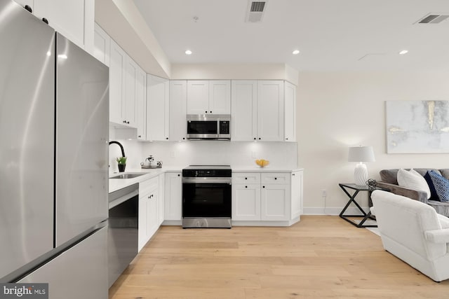 kitchen featuring sink, appliances with stainless steel finishes, light wood-type flooring, and white cabinets